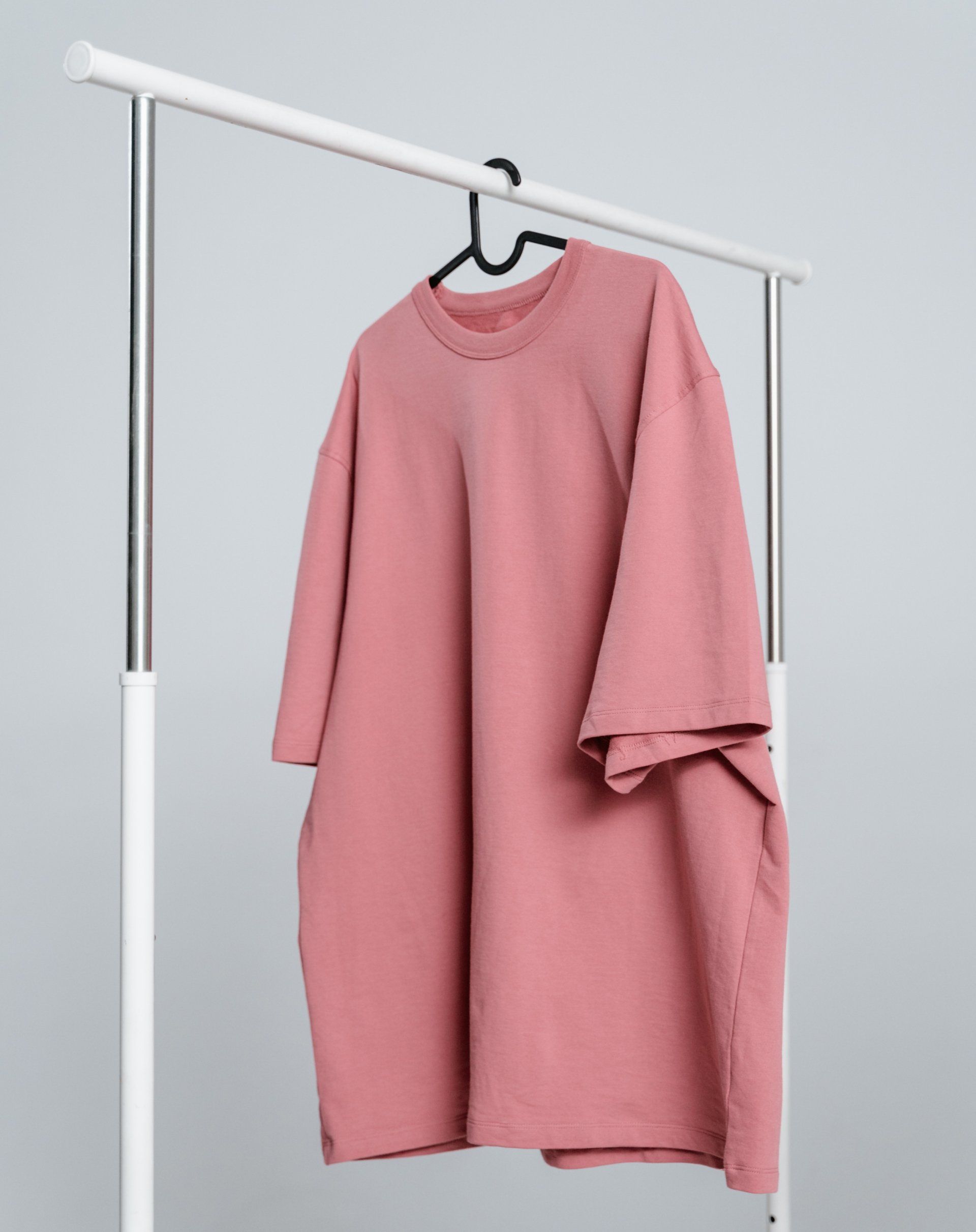 A pink t-shirt is hanging on a rack.