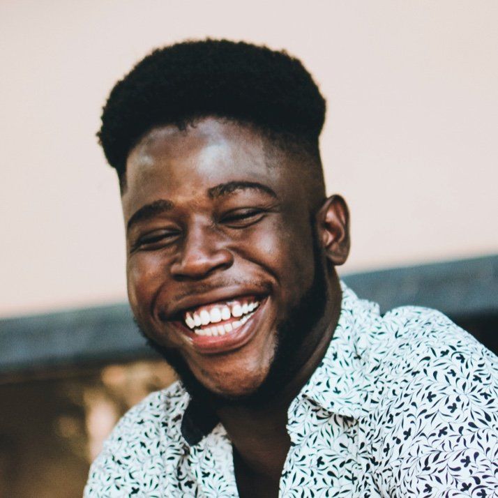 A man with a beard is smiling and wearing a white shirt
