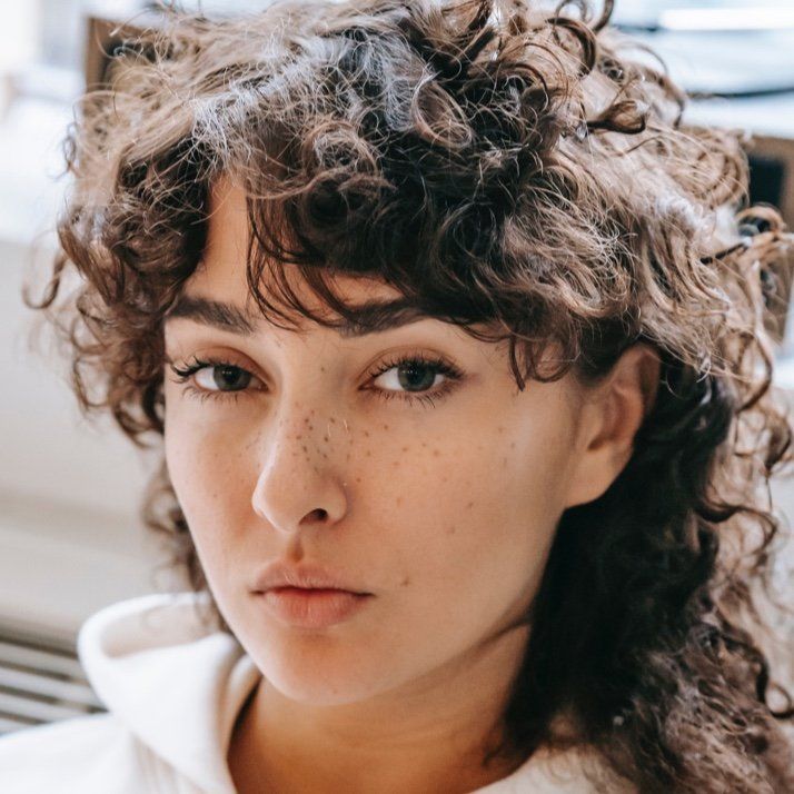 A close up of a woman 's face with curly hair and freckles