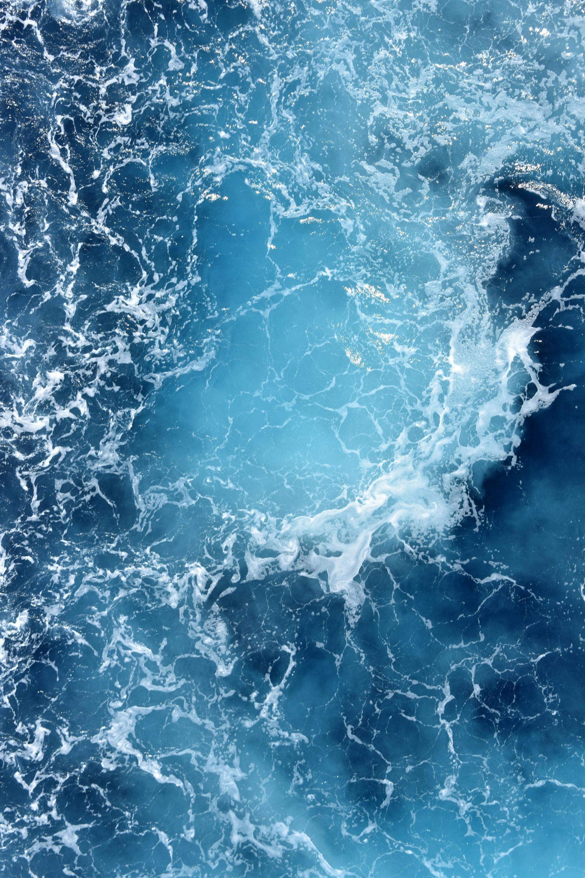 Blue ocean water, foamy waves, and churning surface.