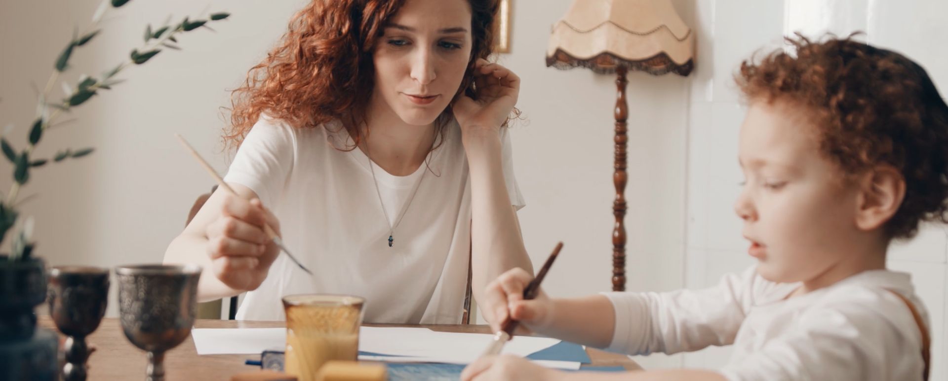 A woman is sitting at a table with a child.