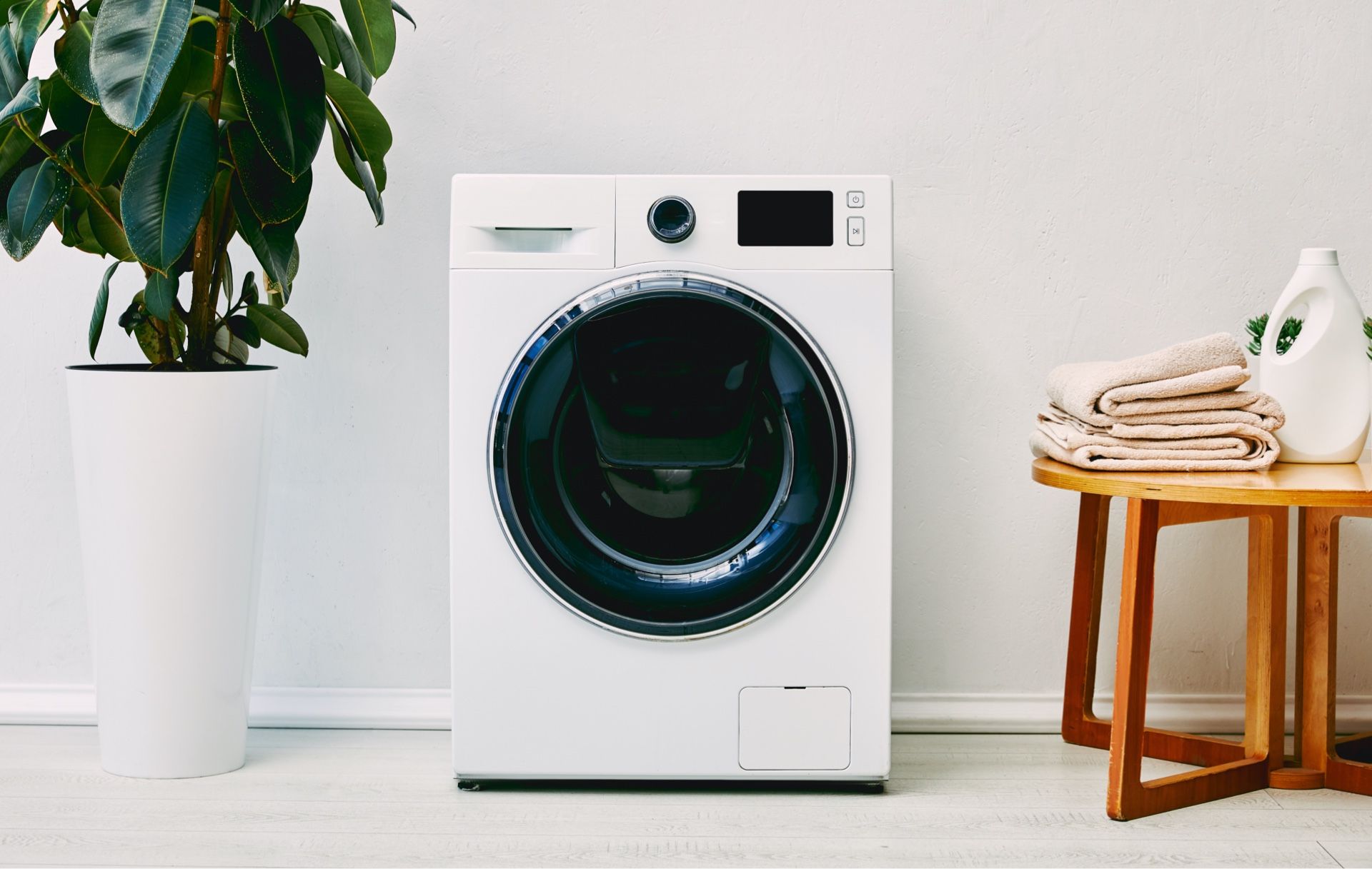 Cozy porch with a hanging white wicker chair and a yellow cushion. A potted plant sits on the wooden floor.
