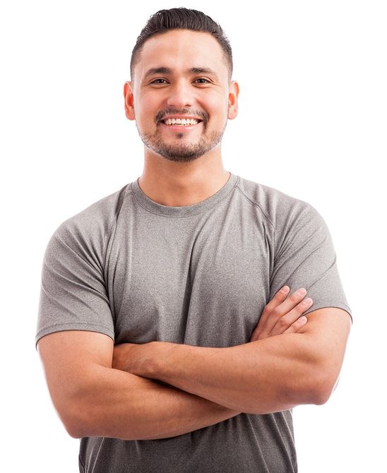A man in a grey shirt is smiling with his arms crossed