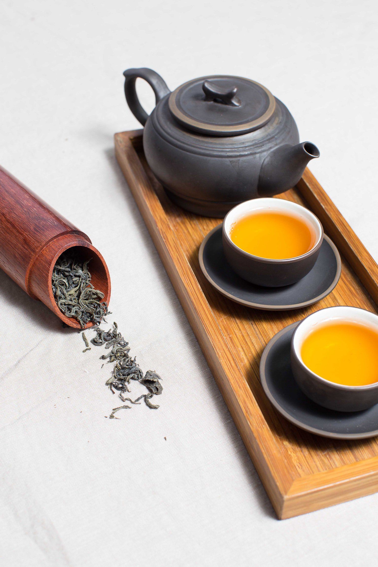Three cups of tea and a teapot on a wooden tray