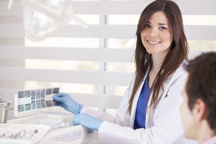 A female dentist is smiling while talking to a patient