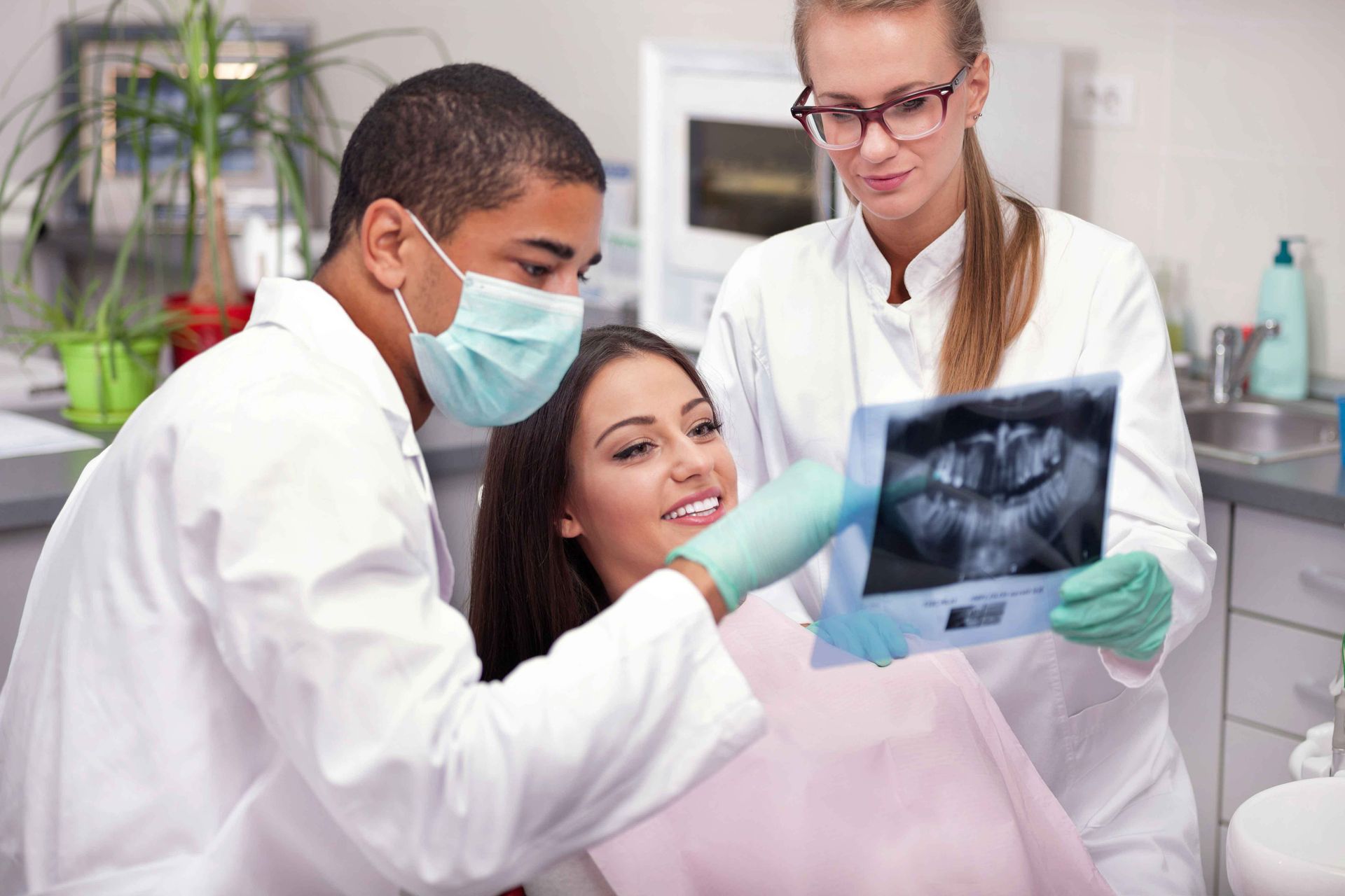 Two dentists are looking at an x-ray of a patient 's teeth.
