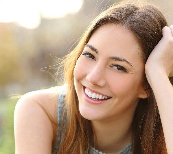 A woman is smiling with her hand in her hair