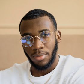 Man with glasses and beard, wearing a white shirt, looking at the camera.