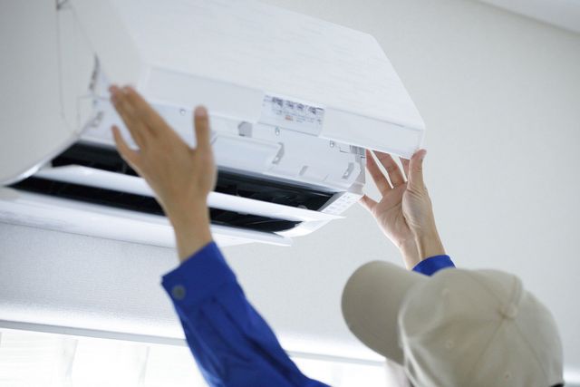 A man is fixing an air conditioner on the wall.