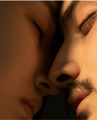 A close up of a man and woman 's faces with their eyes closed.