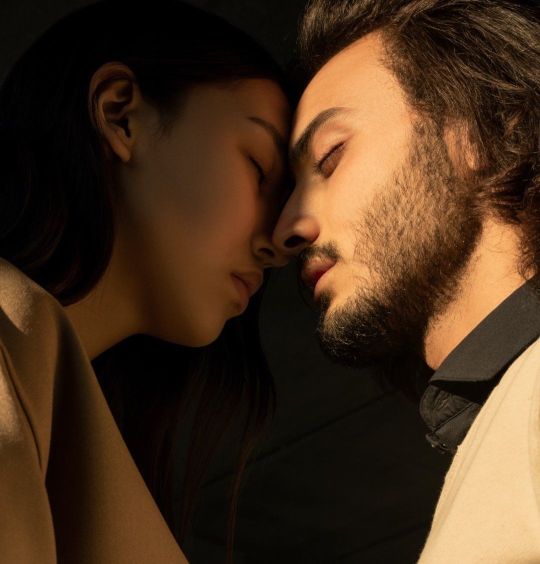 A man and a woman are looking at each other with their eyes closed.