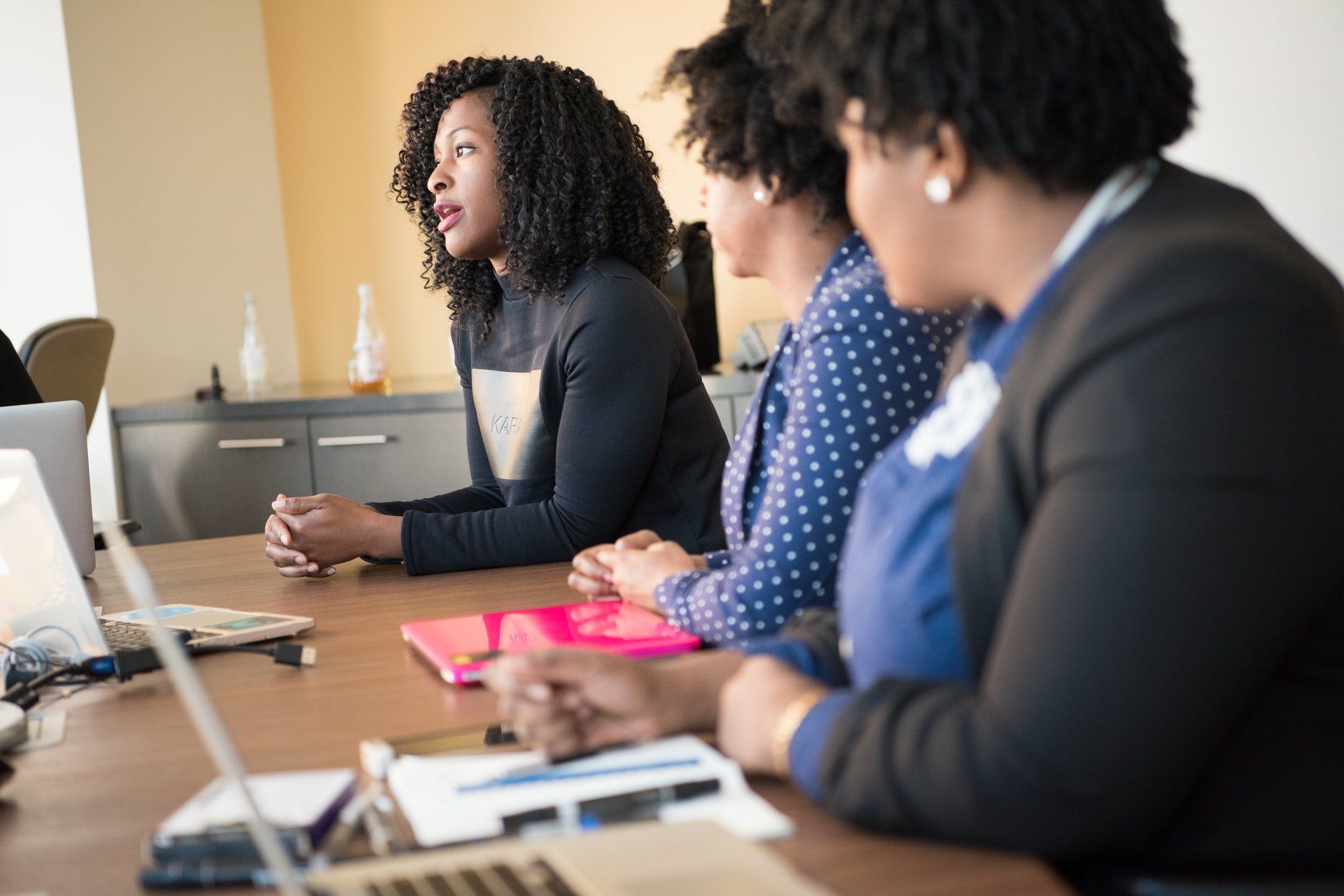 A group of women are sitting at a table having a meeting.