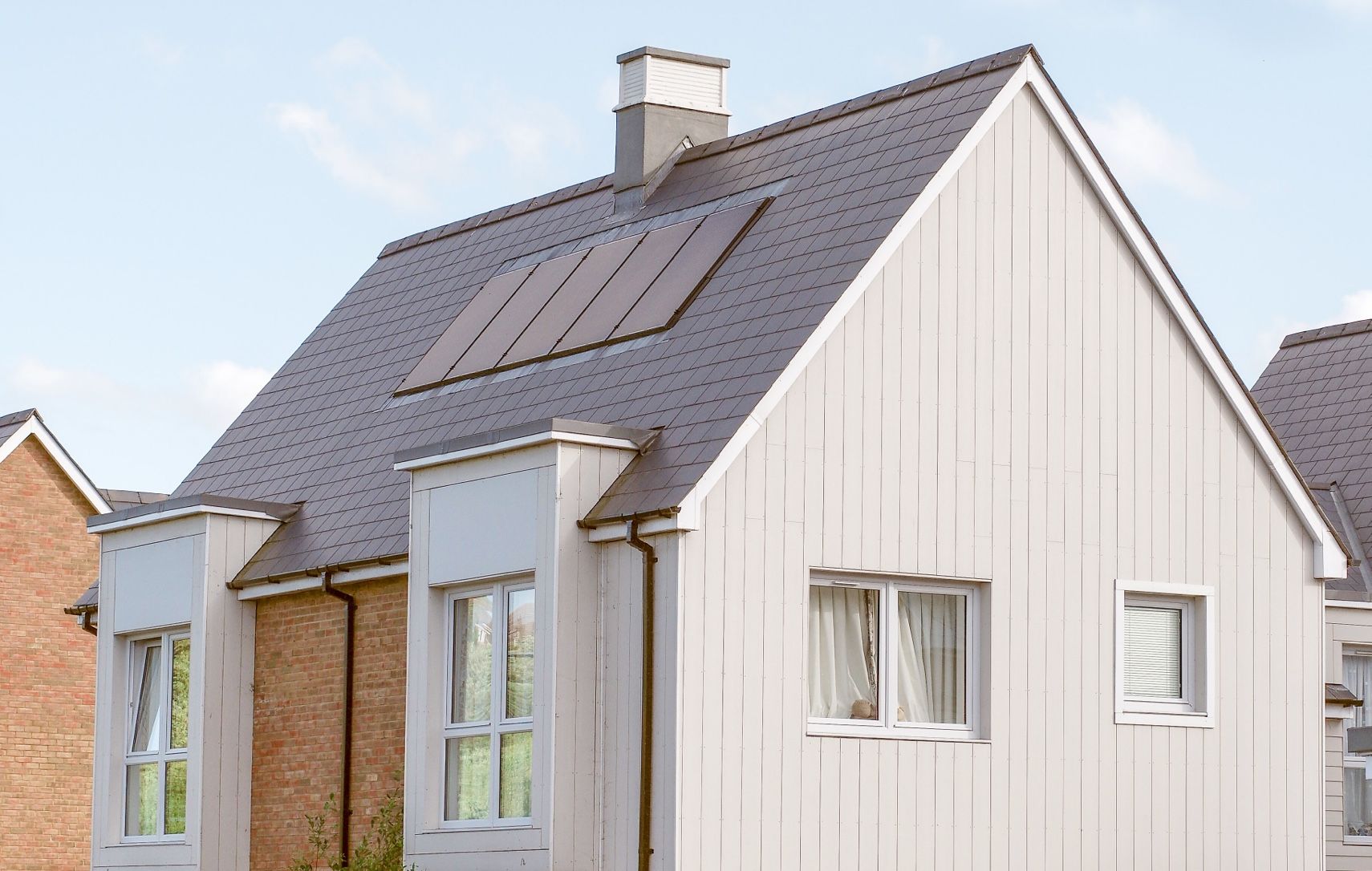 Modern house with gray roof, white siding, and solar panels.