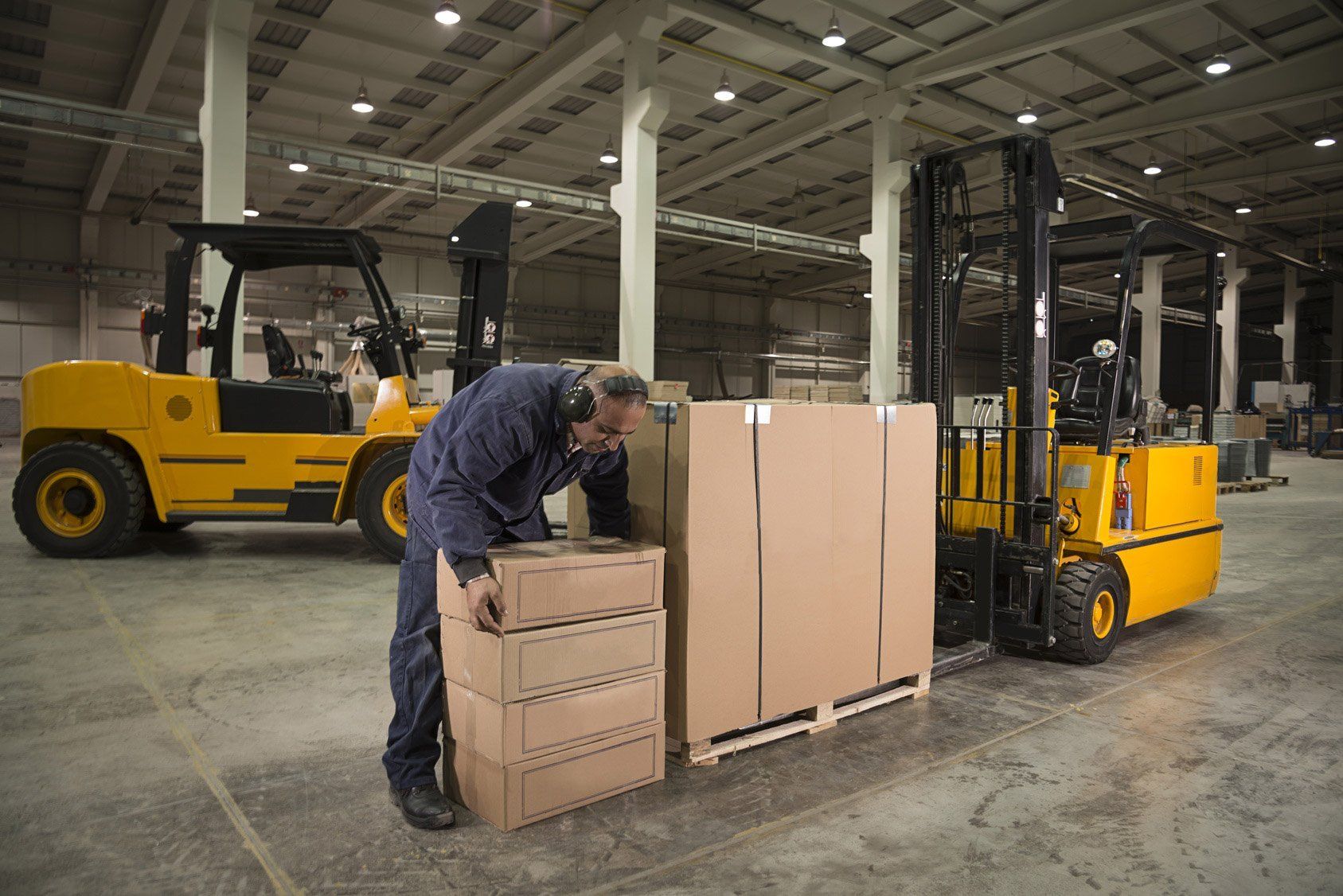 A man is loading boxes into a forklift in a warehouse.