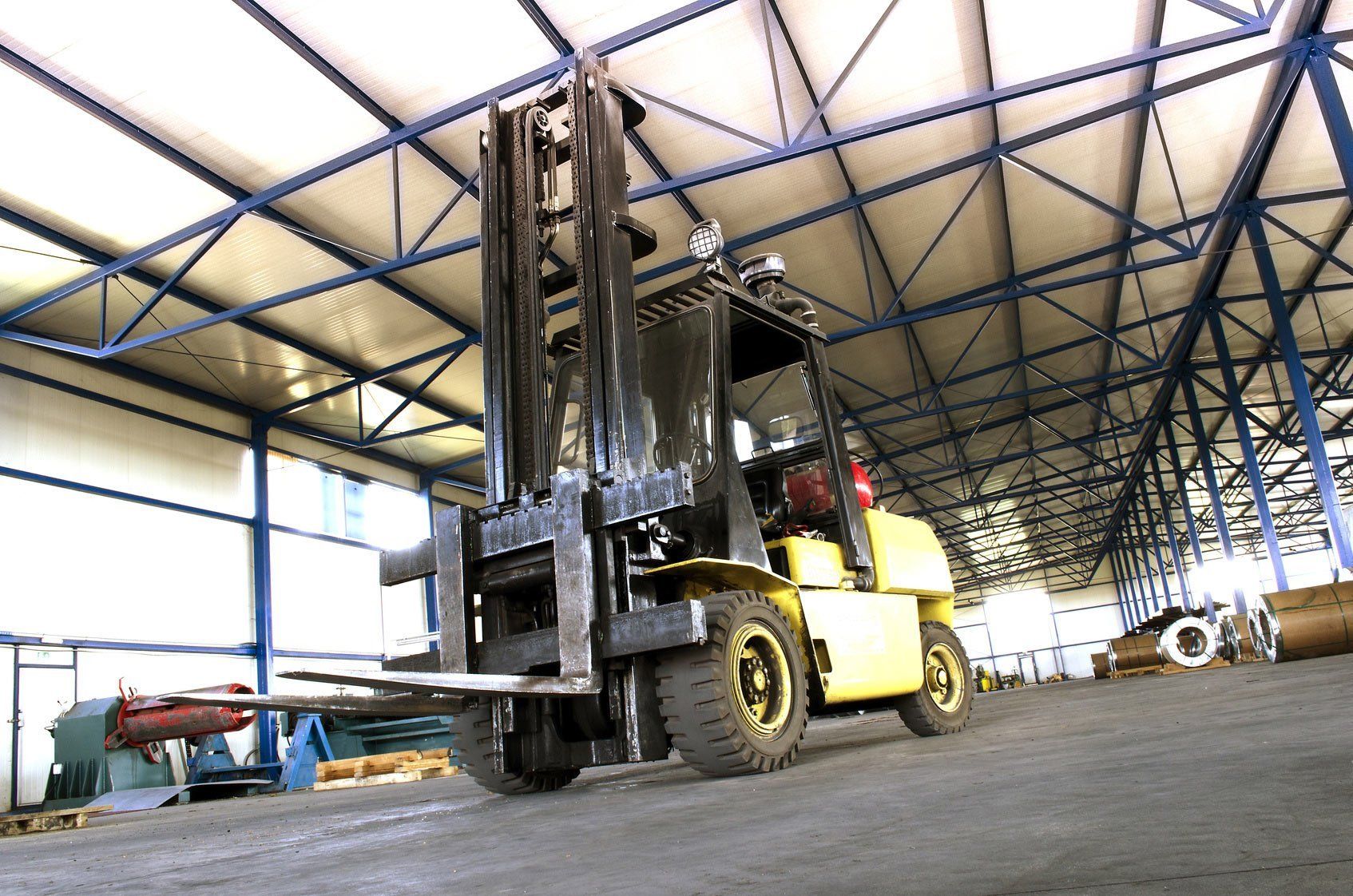 A yellow forklift is parked in a large warehouse