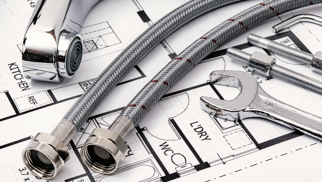A hose and a wrench are on top of a blueprint.