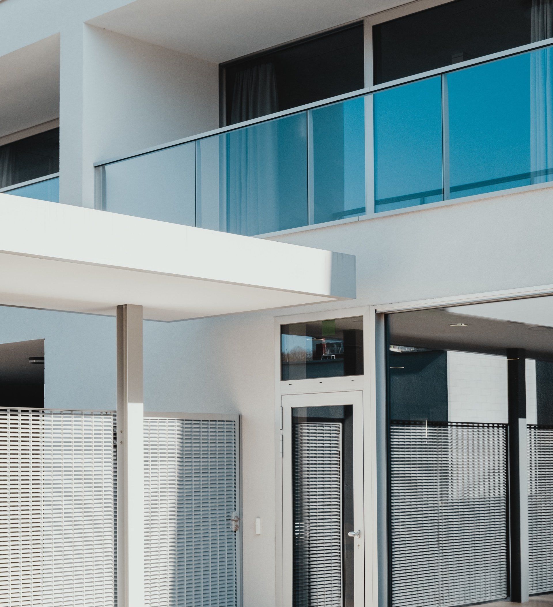 A white building with a blue glass balcony