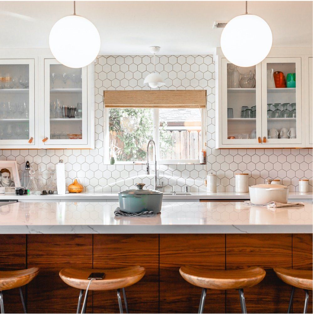 A kitchen with a large island and wooden stools.