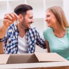 A man and woman are sitting in a cardboard box and the man is holding a key