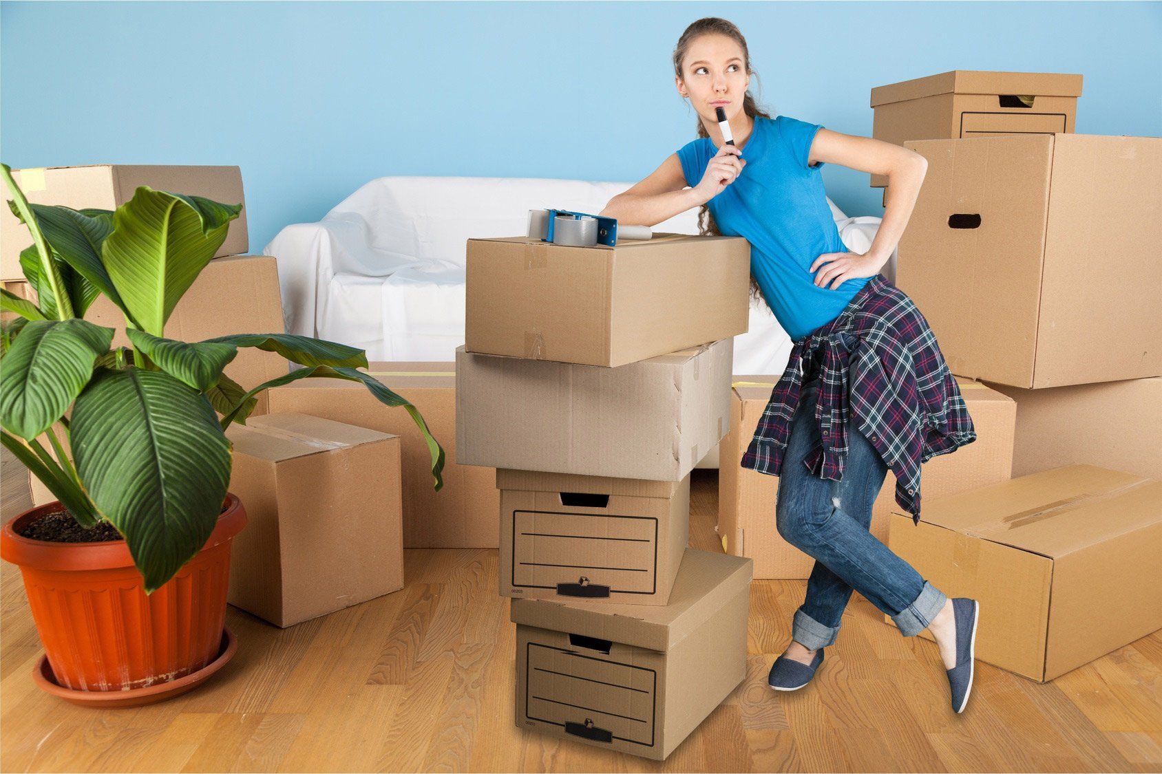 A woman is standing next to a pile of cardboard boxes in a living room.