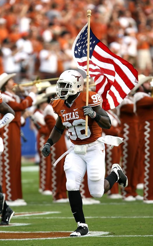 a texas football player is running on the field holding an american flag