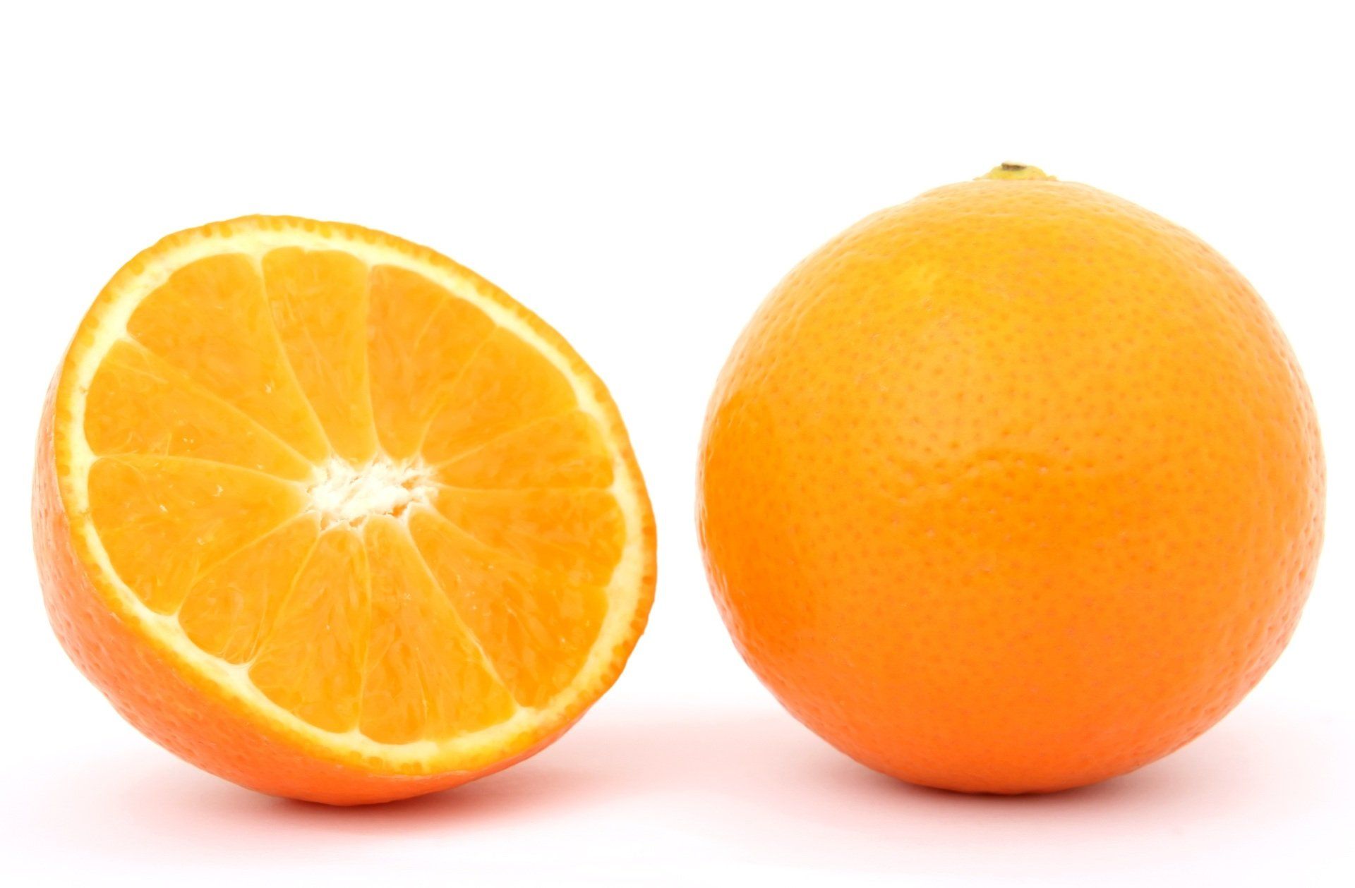 Two oranges are cut in half on a white background