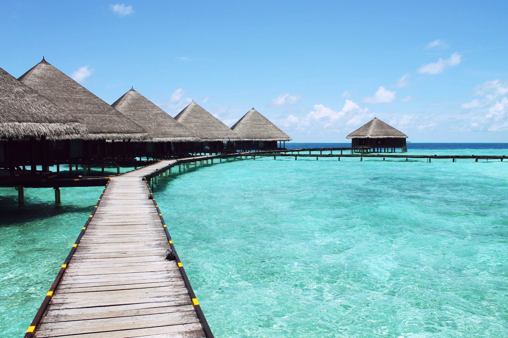 A wooden pier leading to a row of bungalows in the ocean