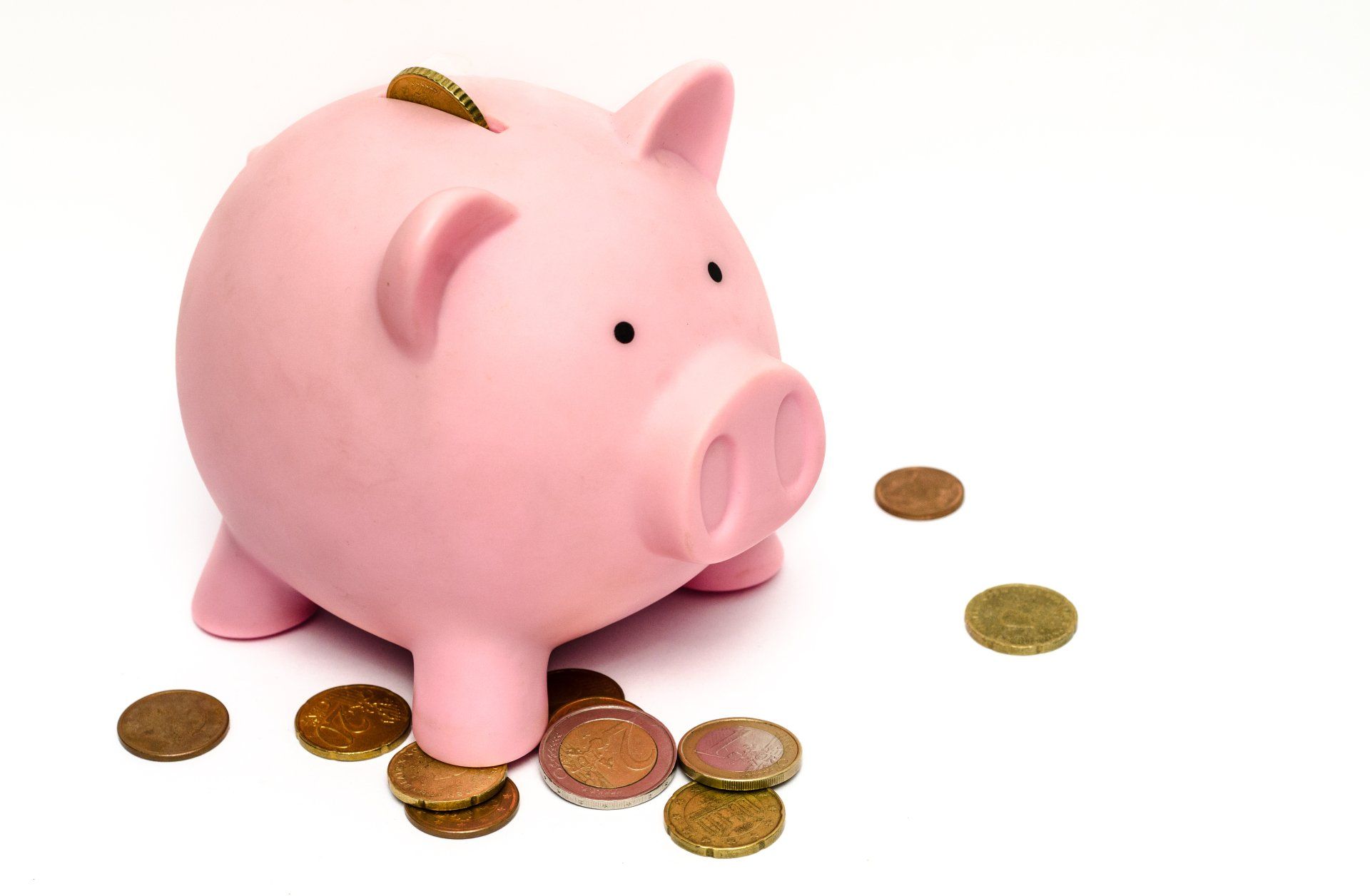 a pink piggy bank surrounded by coins on a white background