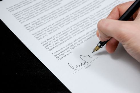 A person is signing a document with a fountain pen