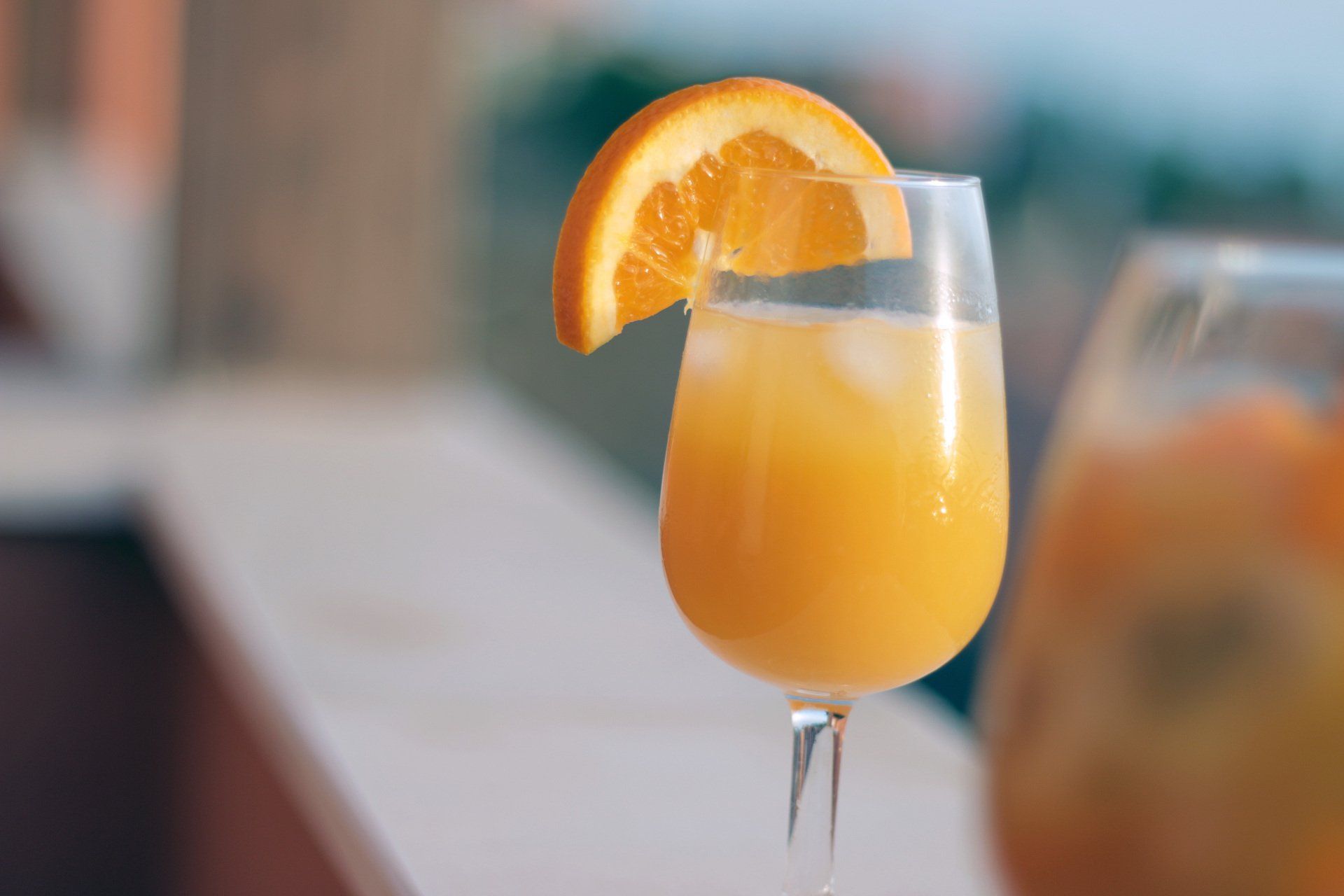 A close up of a glass of orange juice with an orange slice on top.