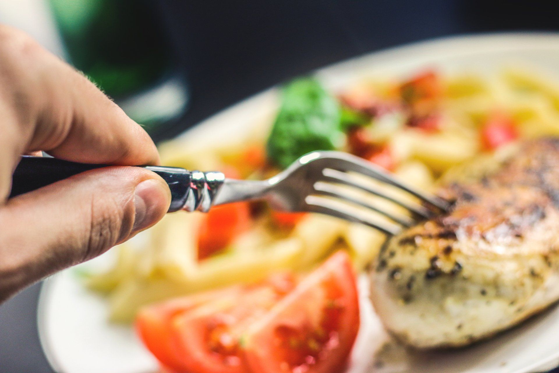 una persona tiene una forchetta sopra un piatto di cibo.