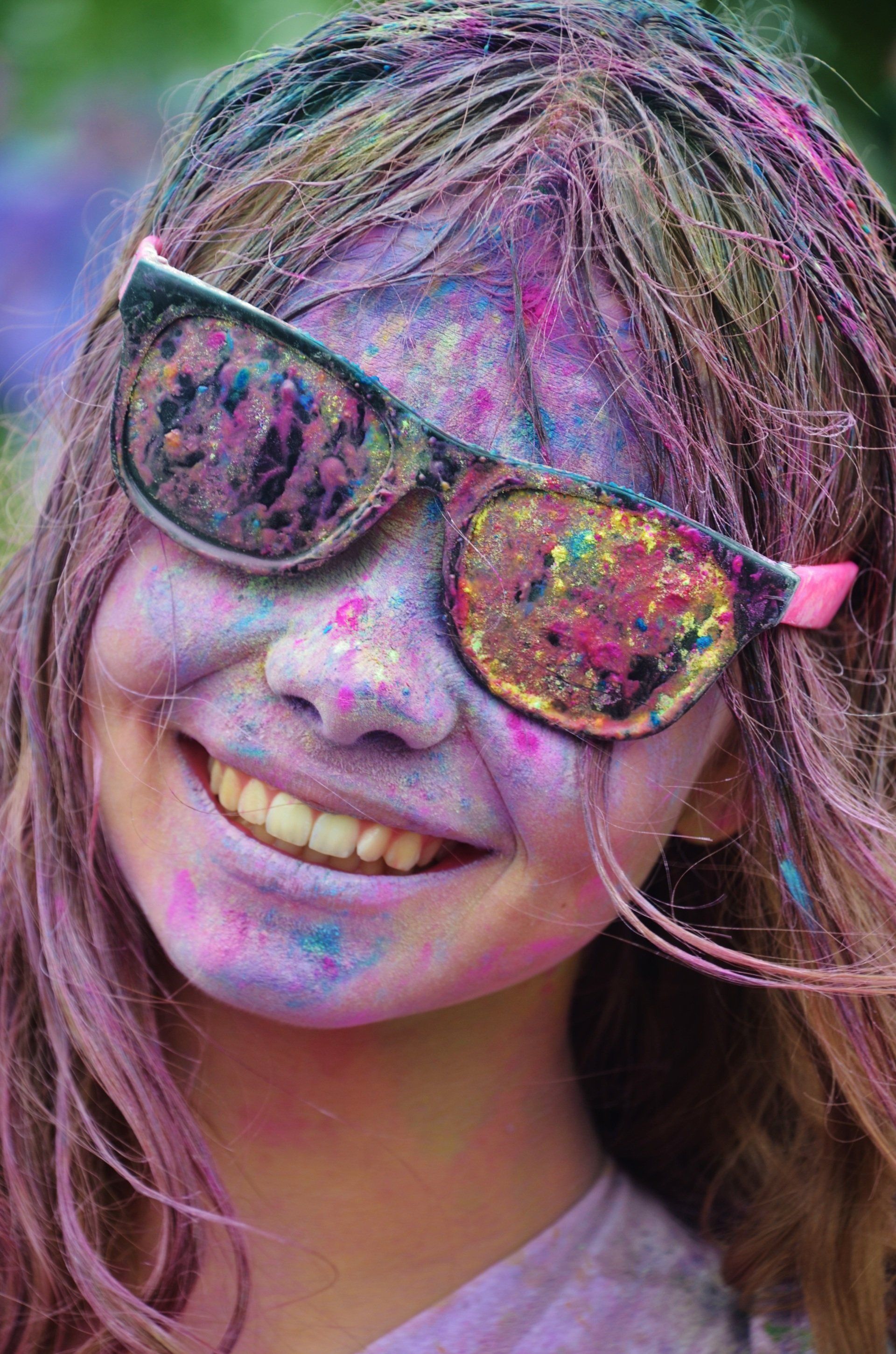 a close up of a girl wearing sunglasses and covered in colored powder .