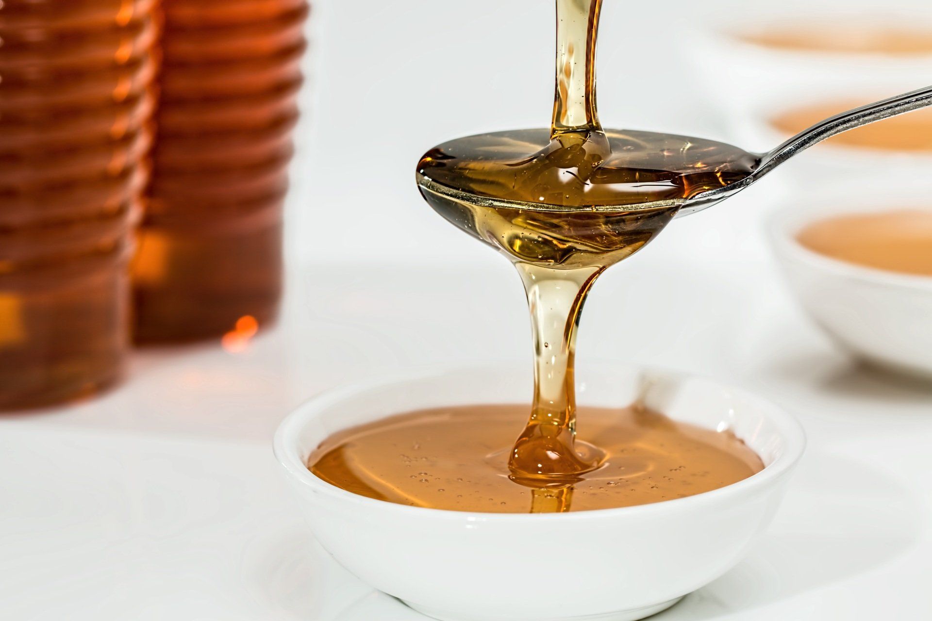 Honey being dripped onto a spoon and overflowing into a bowl