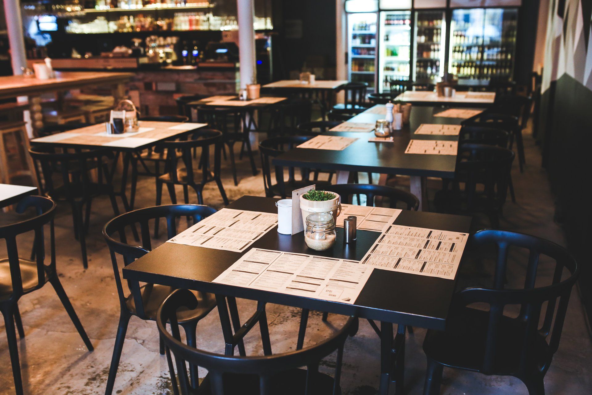 Front restaurant technology dining room with menus on black wooden tables and chairs