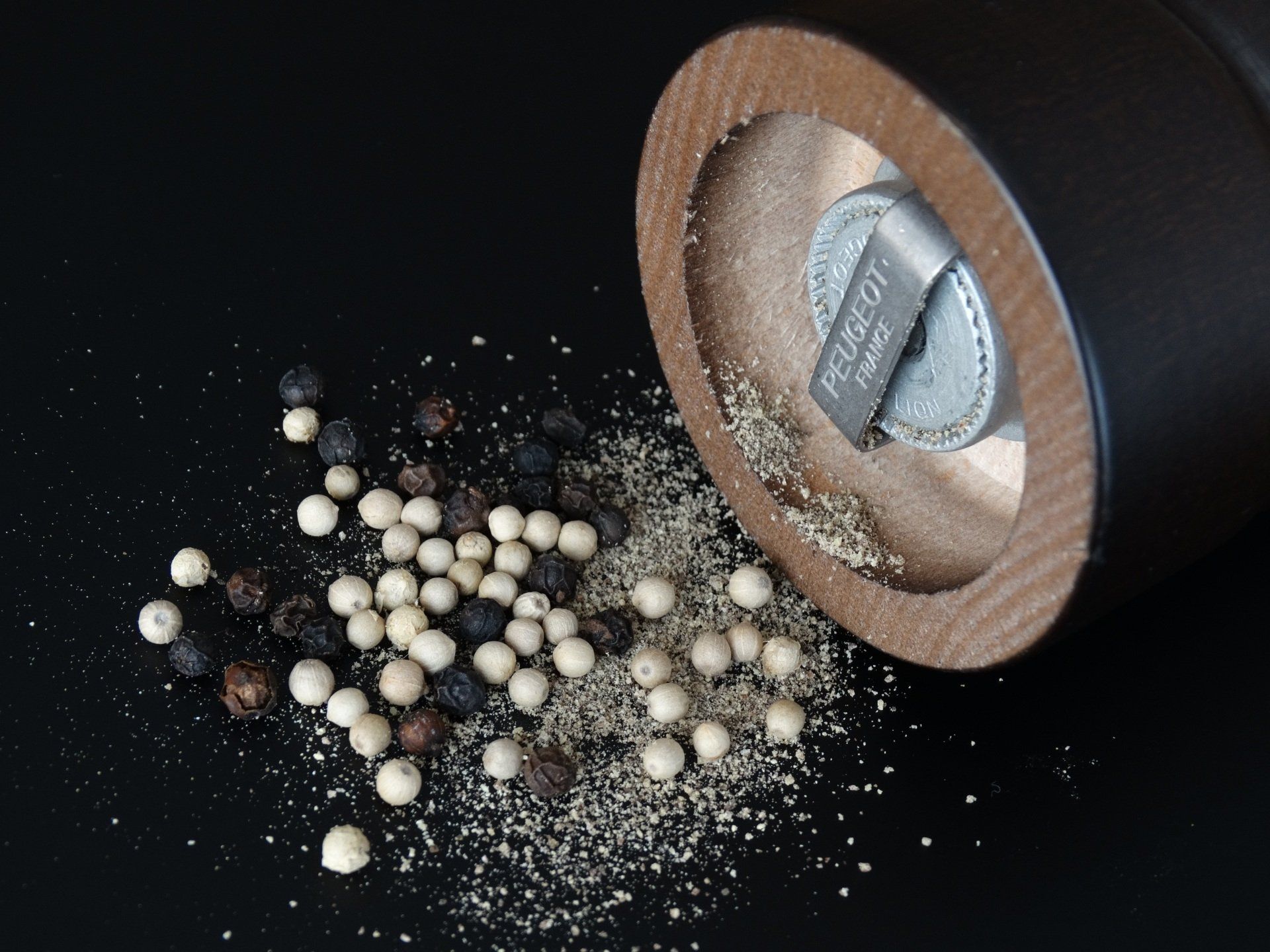 A black and white pepper grinder is being used to grind pepper