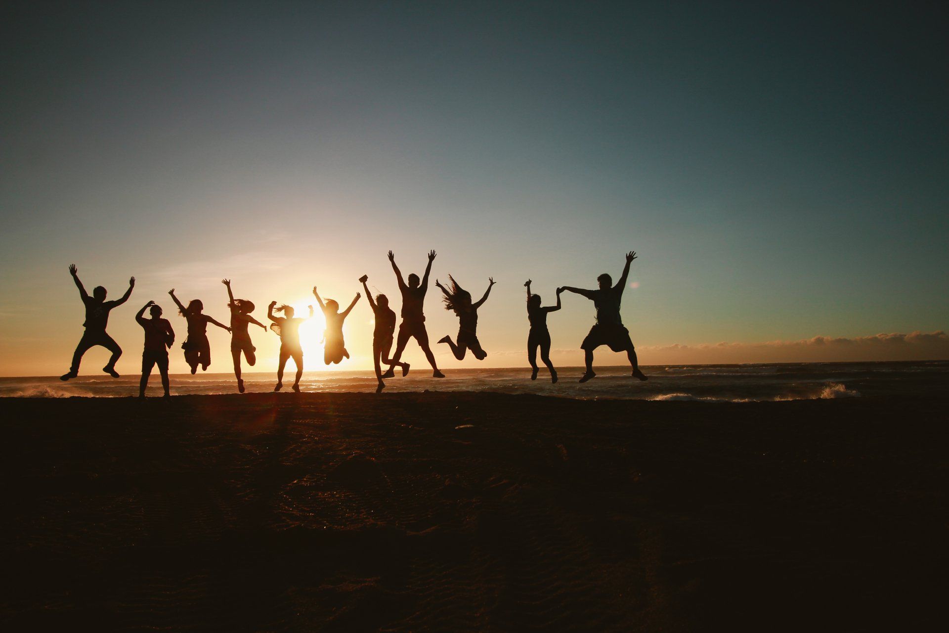 Group of people jumping while facing the sunset