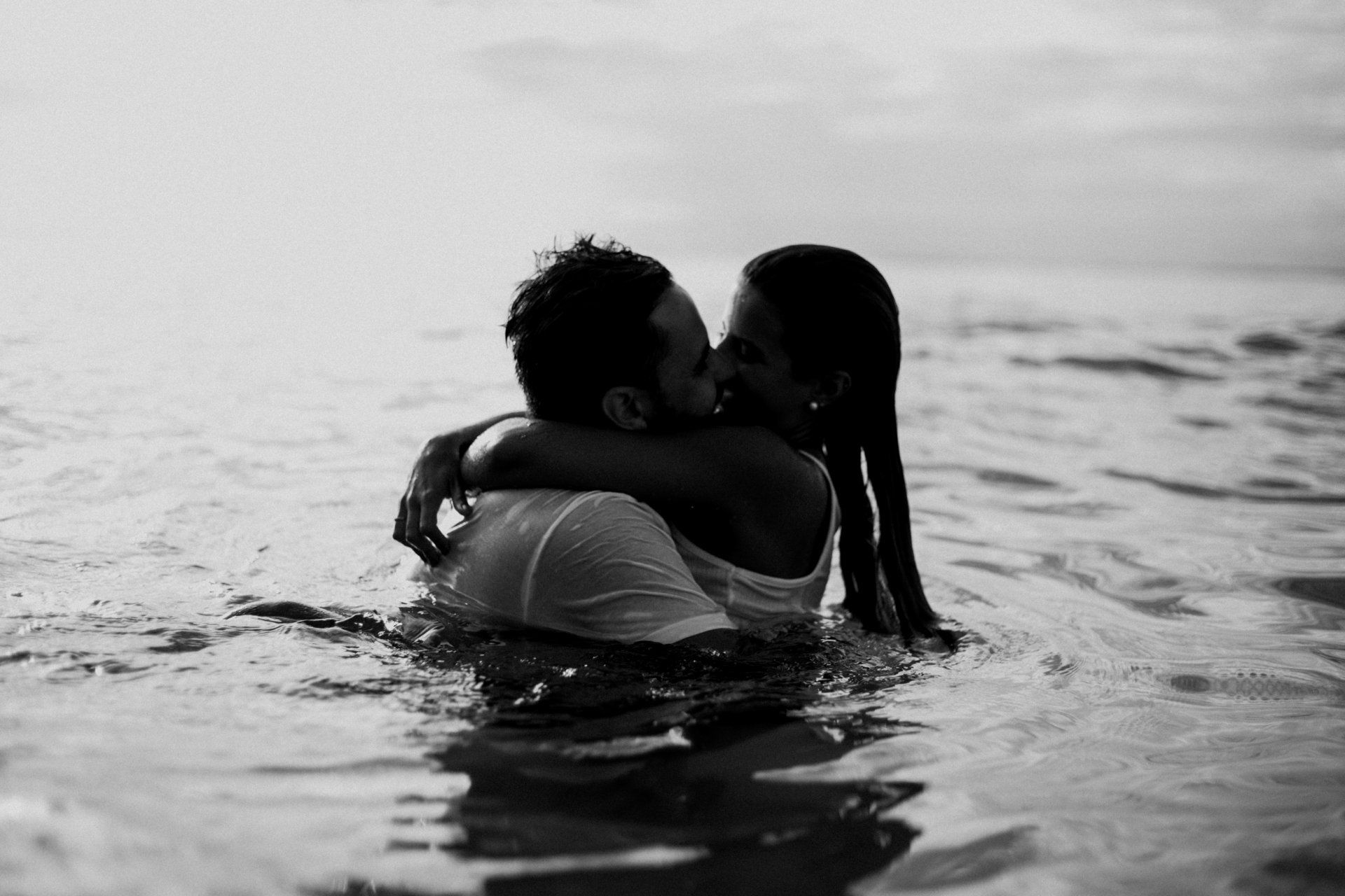couple kissing in the ocean black and white