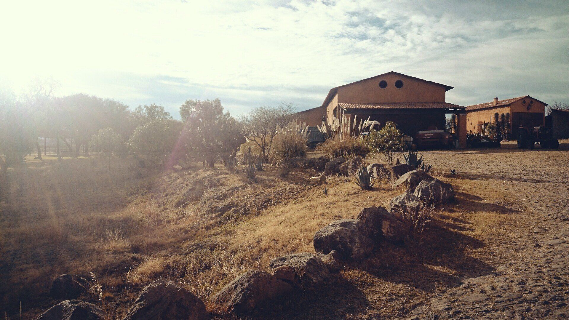 A house is sitting on top of a hill next to a dirt road.