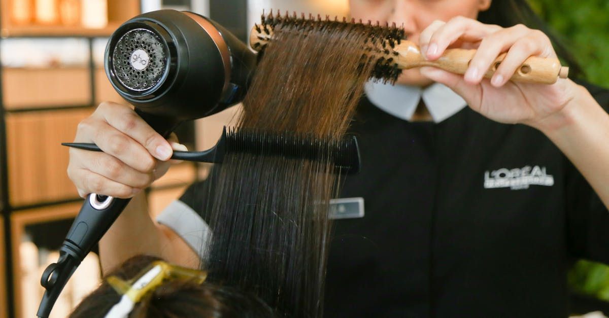 A woman is brushing her hair with a brush and a hair dryer.