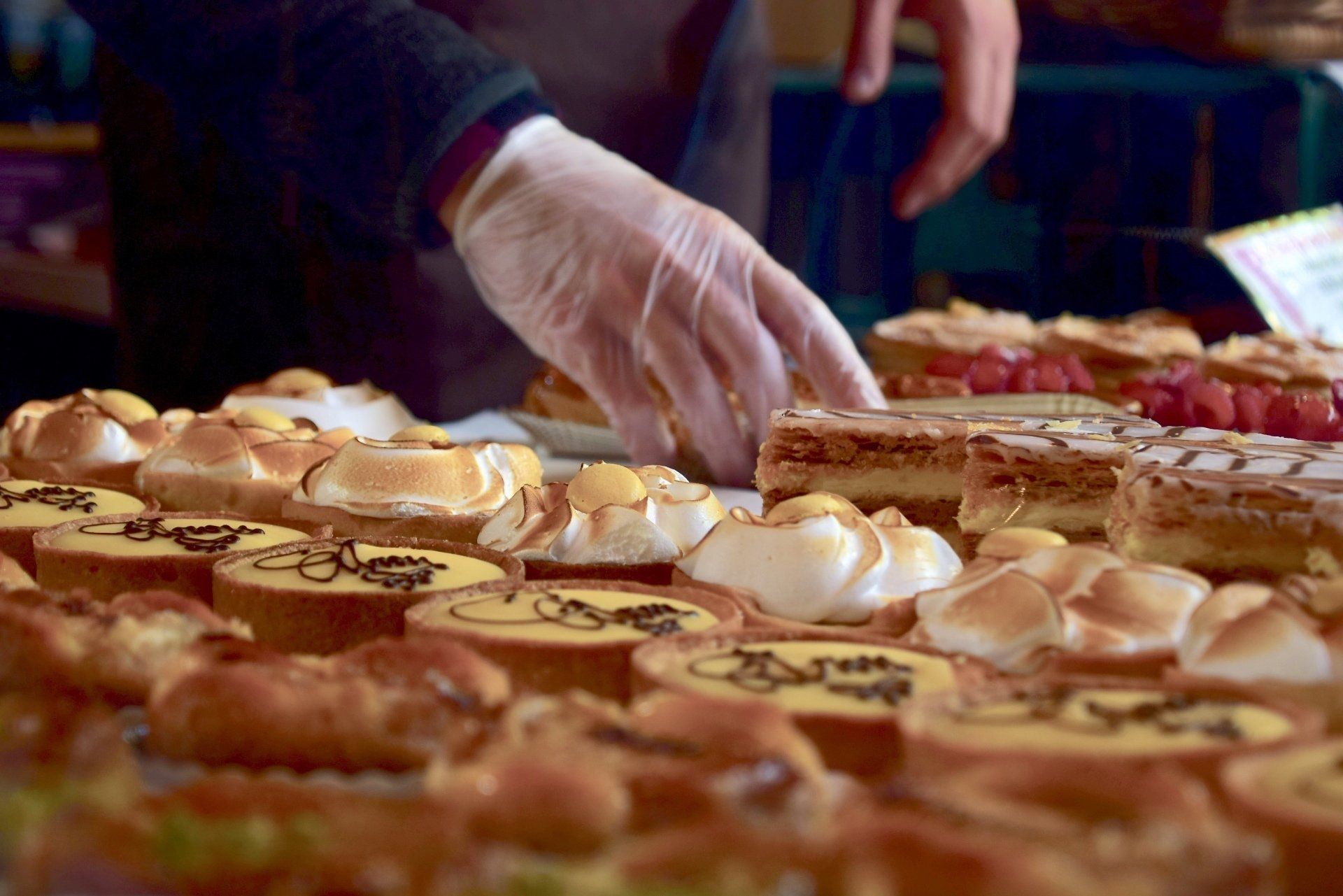 a person wearing gloves is reaching for a pastry on a table .