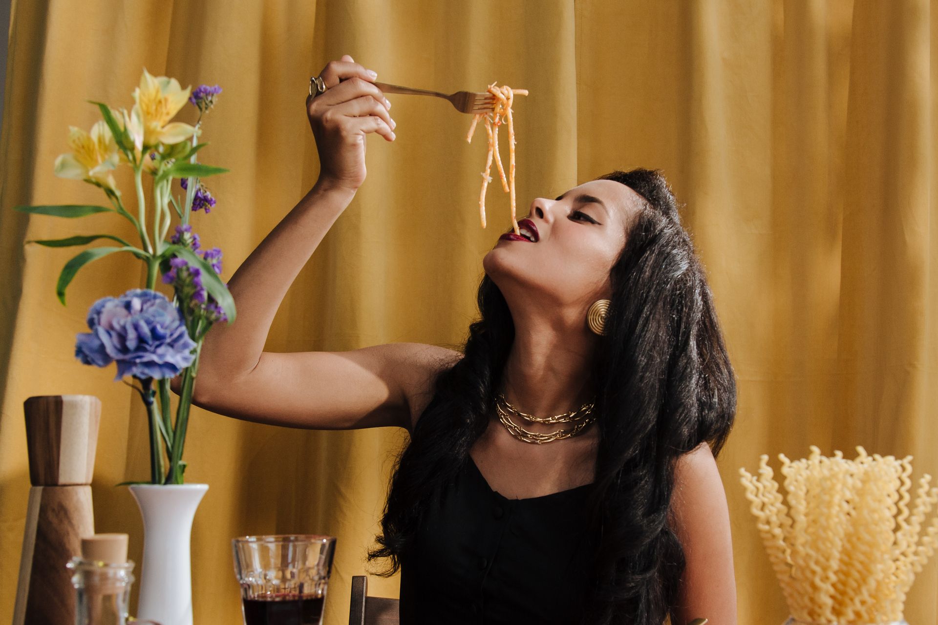 an image of A woman sitting at a dining table, holding up a fork with spaghetti, poised to take a bite at Rudy's Pizza in Newark DE