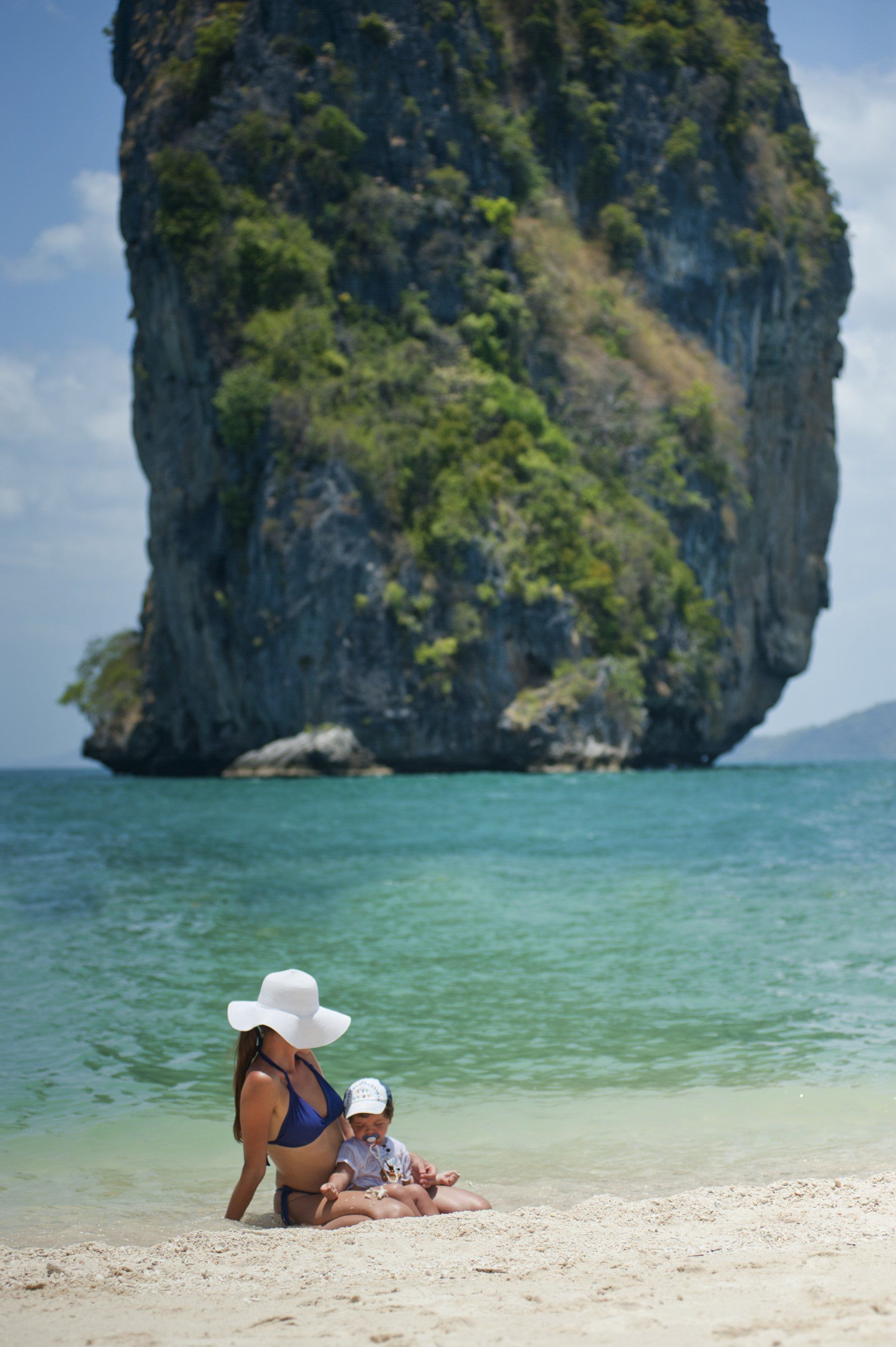 A woman is sitting on the beach with two children.