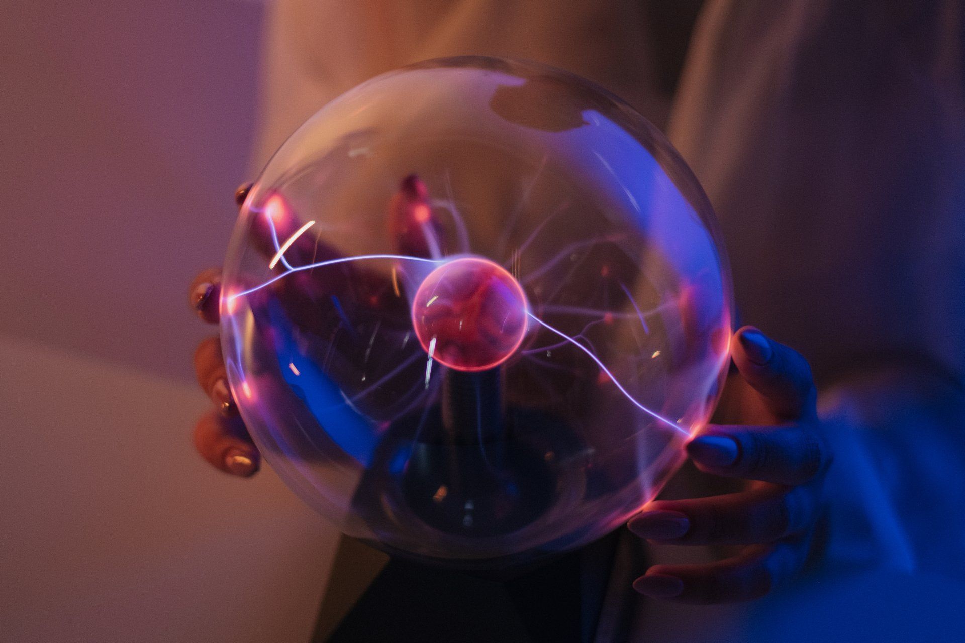 A person is holding a plasma ball in their hands.