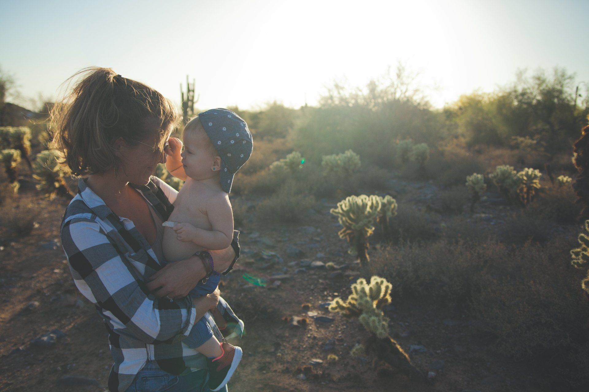 A woman is holding a baby in her arms in the desert.