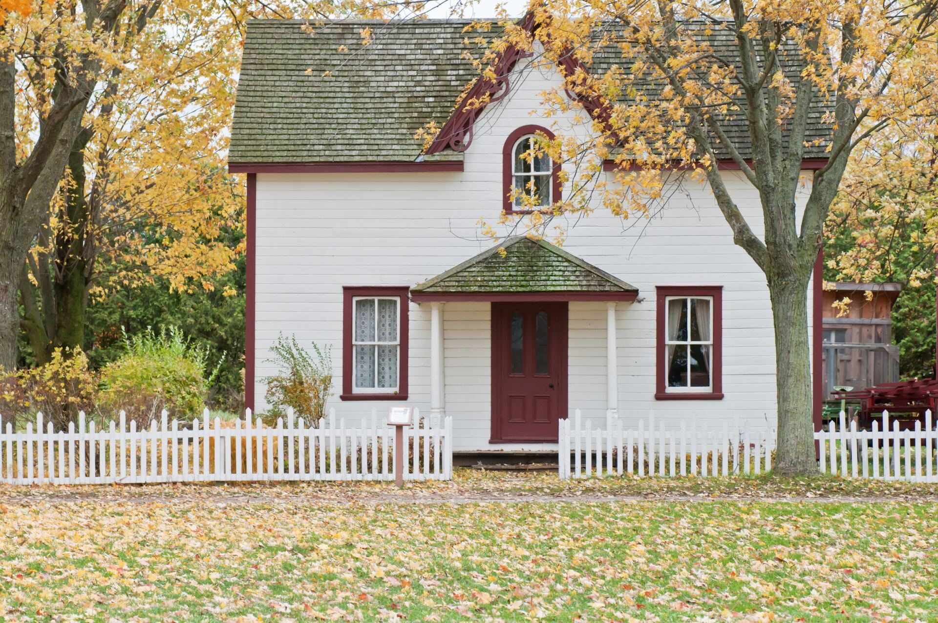 This image shows a two-story house with white siding and a dark red roof.