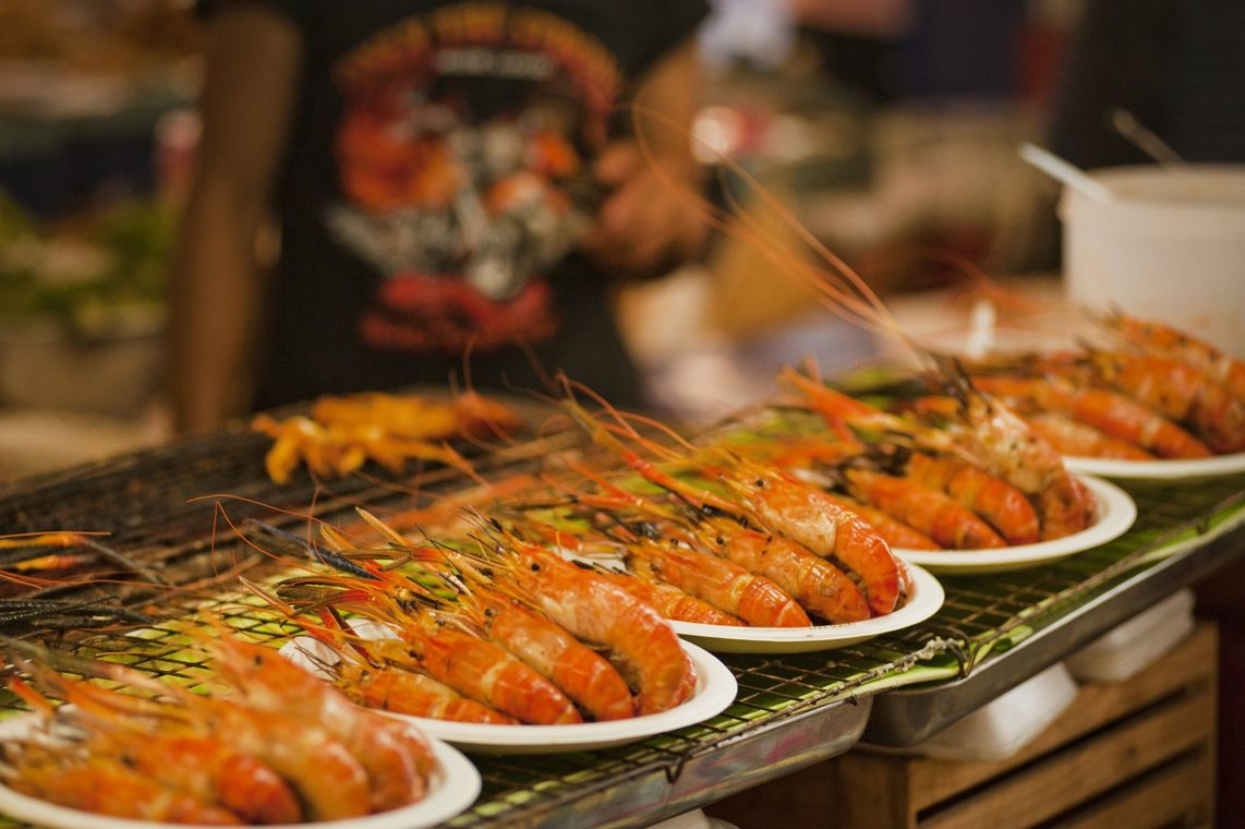 A row of shrimp sitting on plates on a grill.