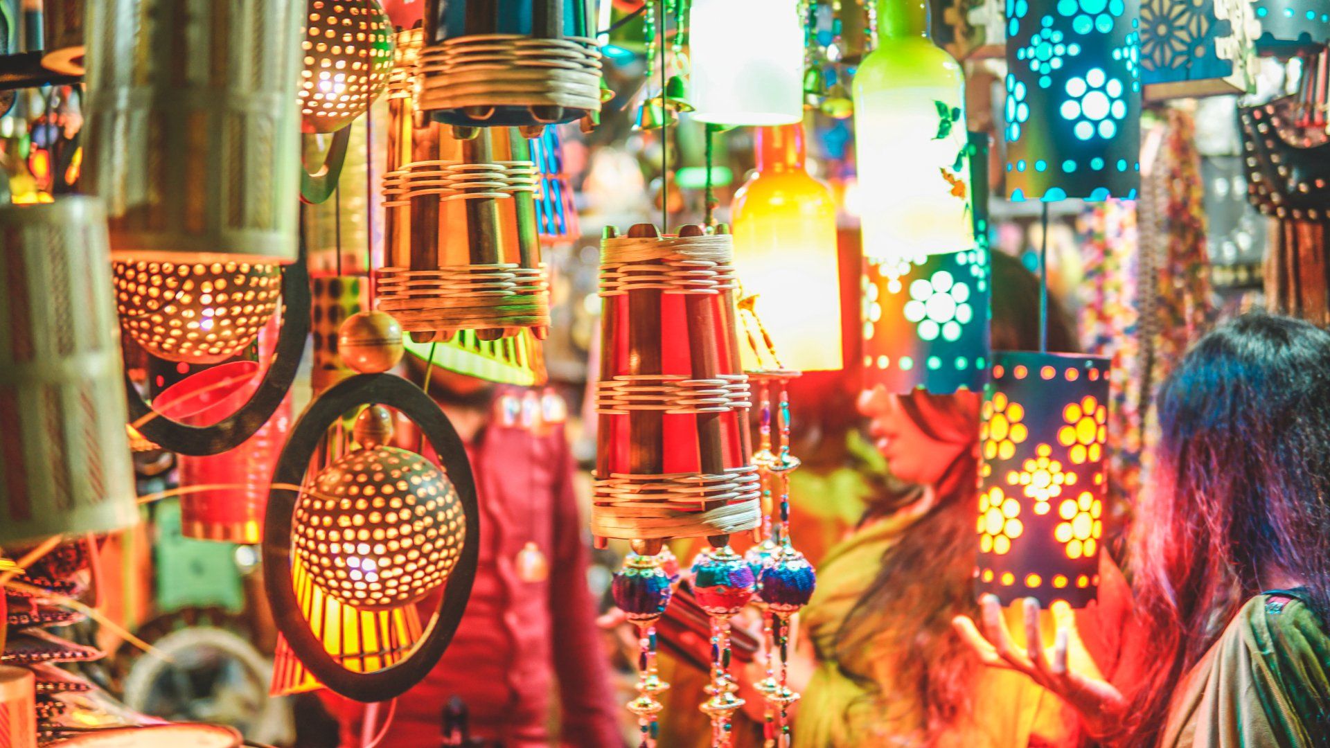 A woman is looking at a bunch of colorful lanterns in a store.