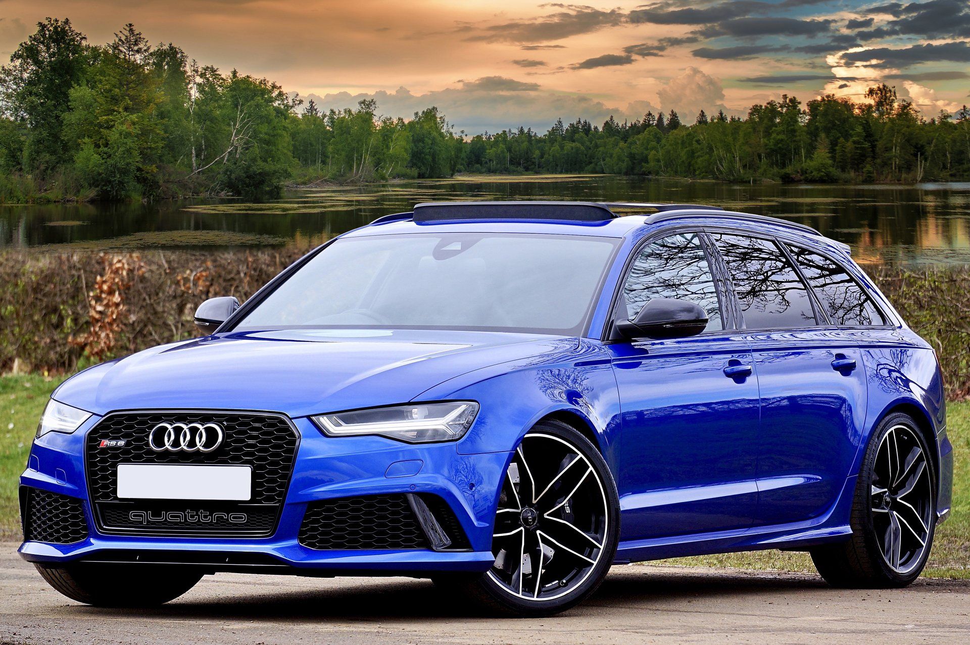 A blue audi rs6 is parked in front of a lake.