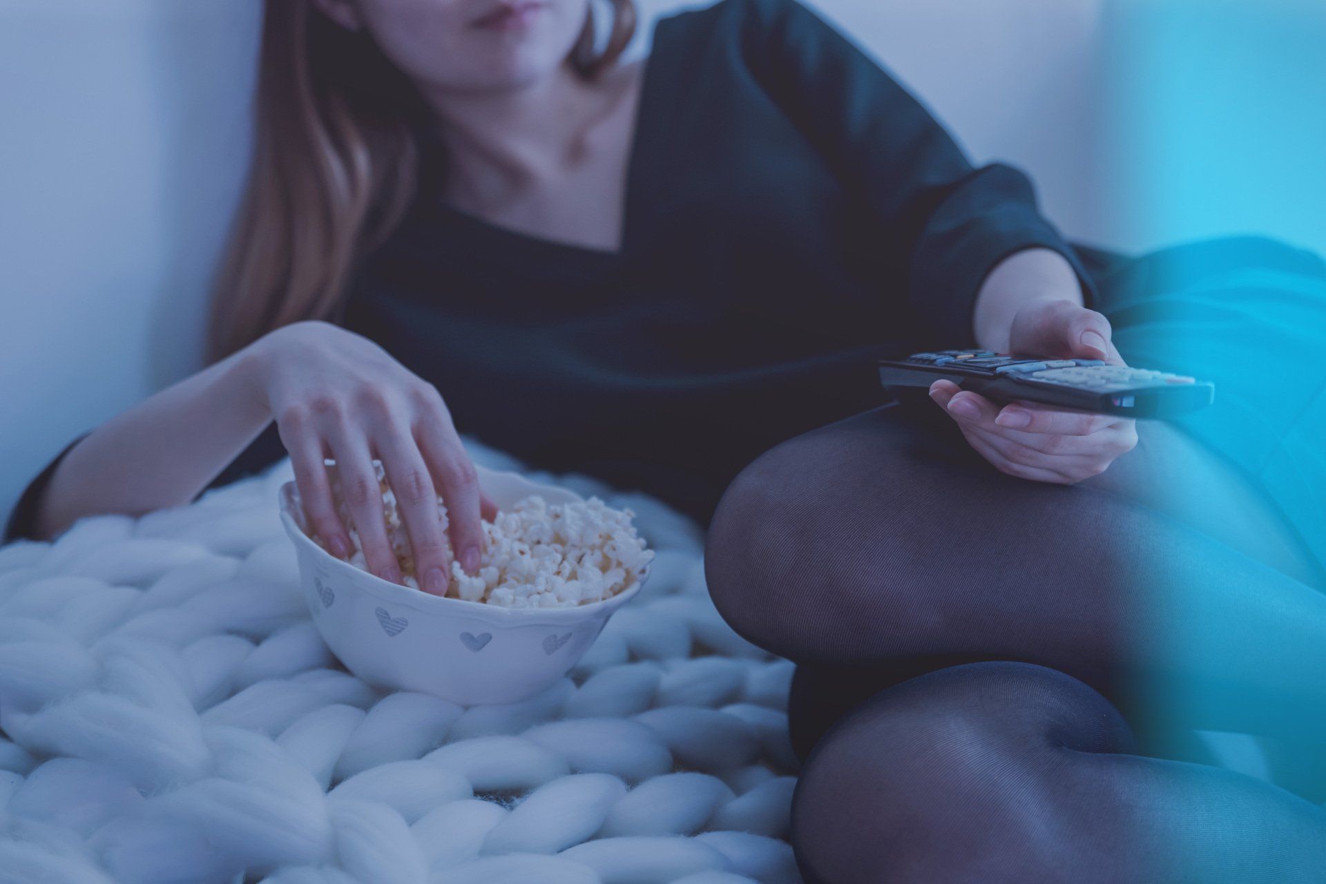 una donna single mangia popcorn mentre tiene in mano il telecomando