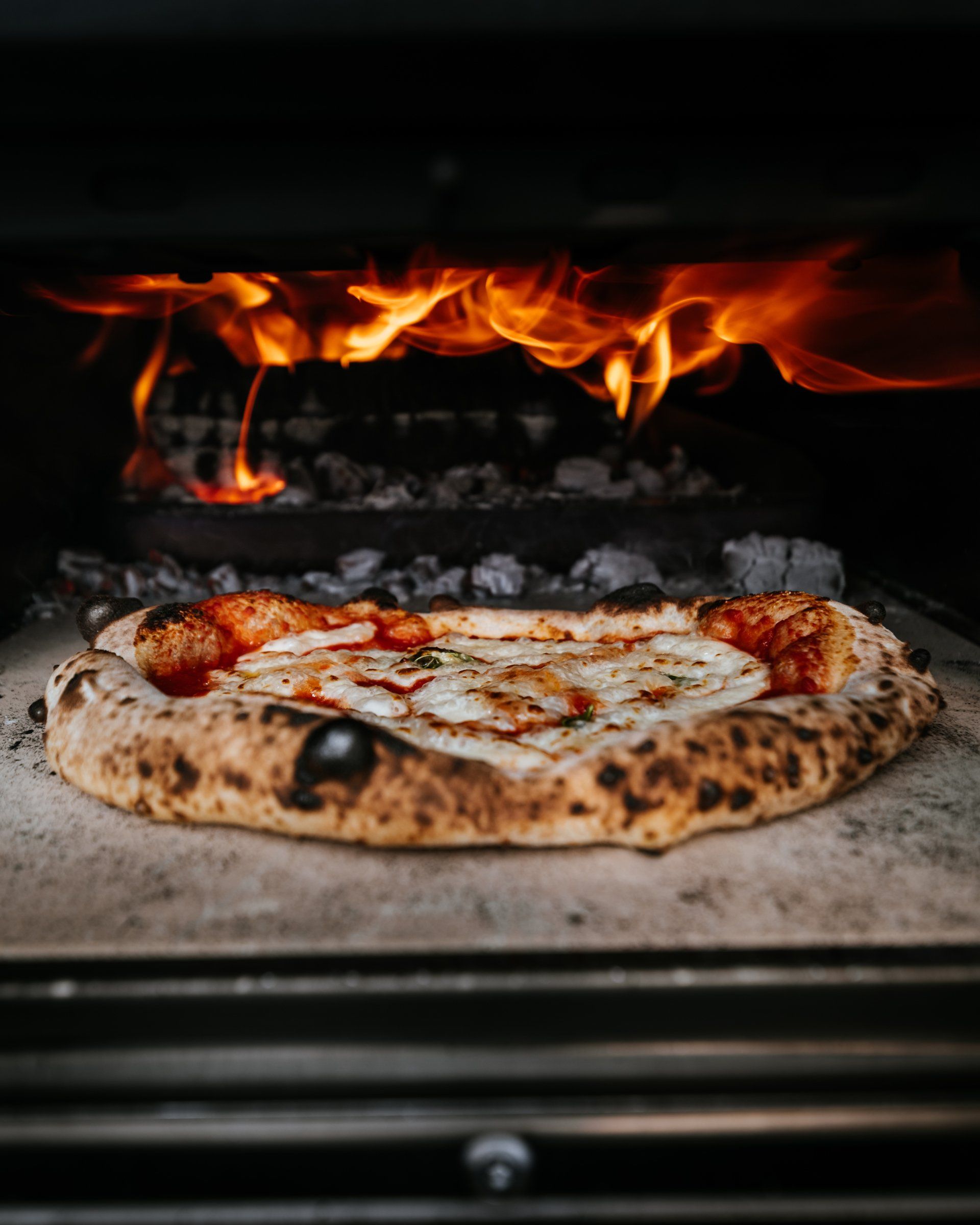 A pizza is being cooked in an oven with flames coming out of it.